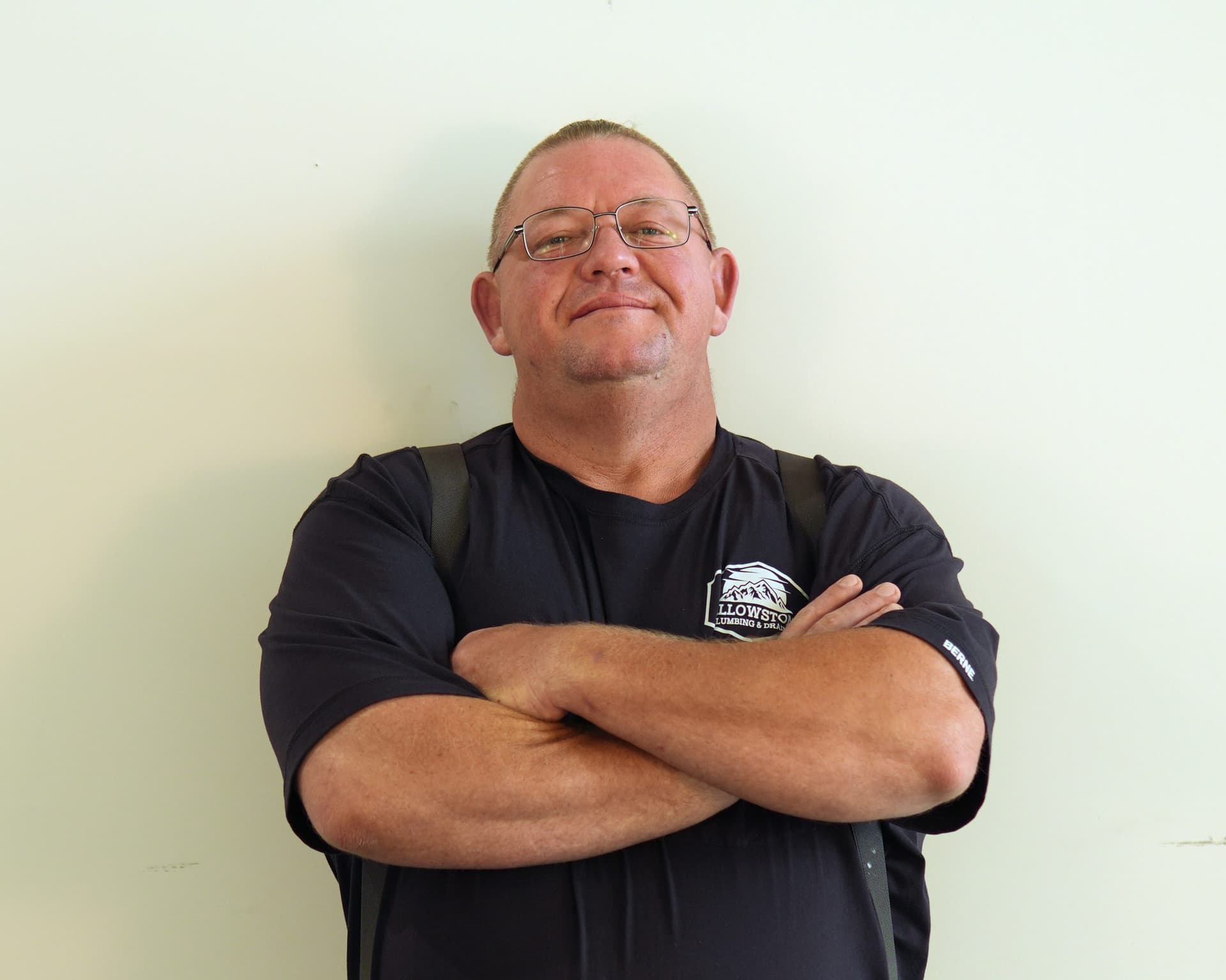 A Yellowstone Plumbing technician, arms crossed, in uniform